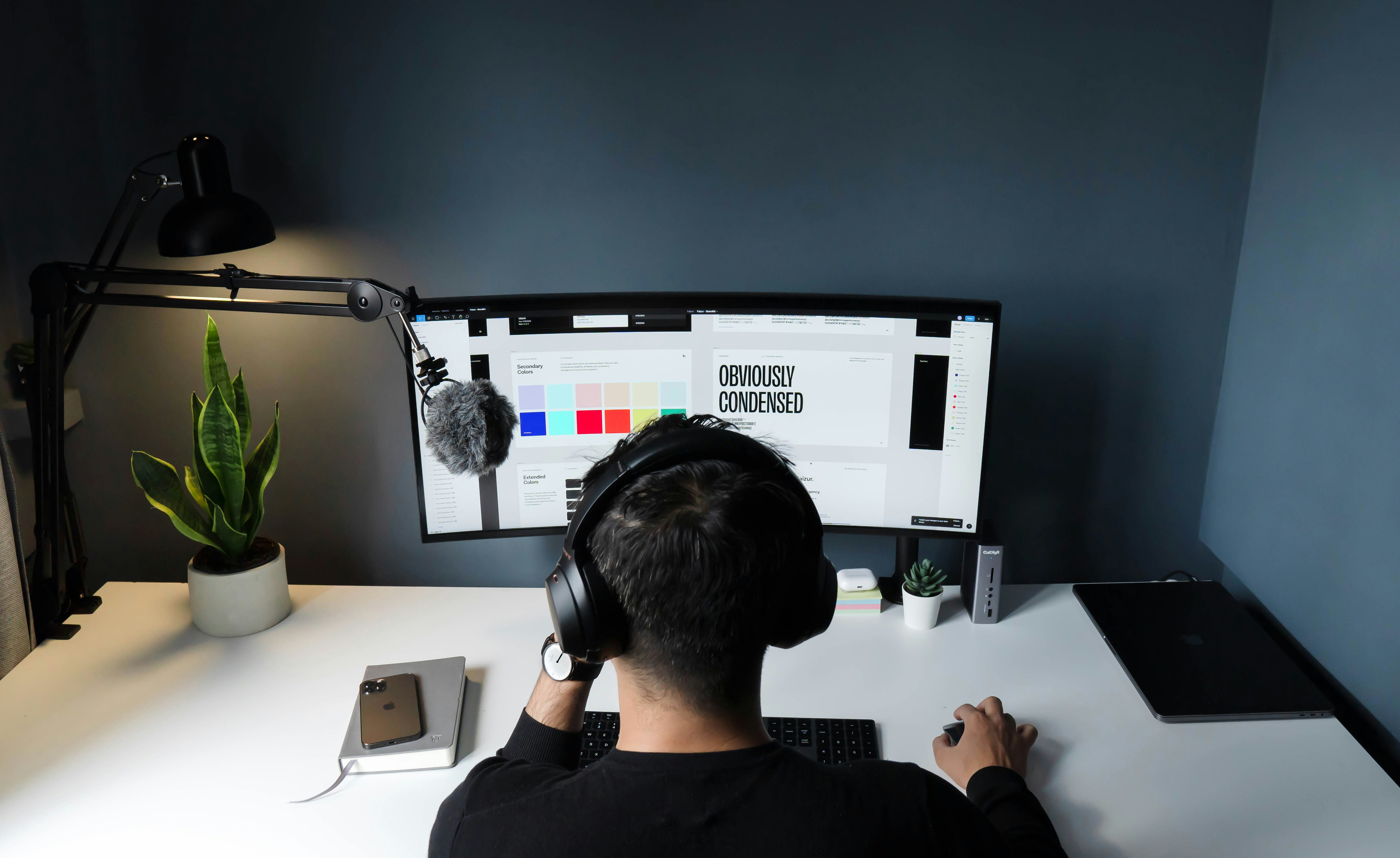 Freelancer working from a home office setup with a large monitor, headset, and microphone—representing the flexibility and independence of 1099 contract work supported by Journey Health’s simplified, affordable healthcare solutions.